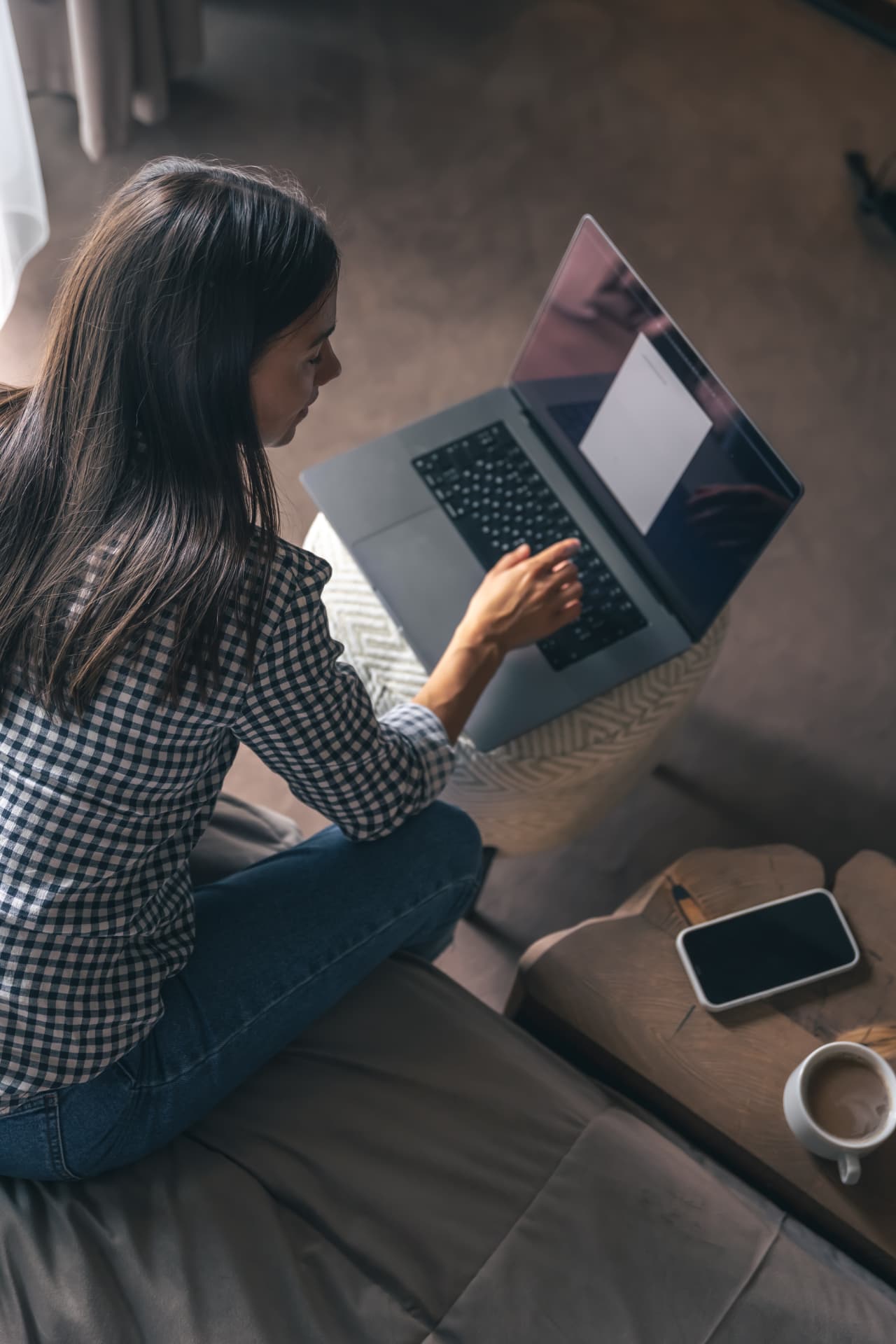 A woman sitting on a sofa at home, working on her laptop